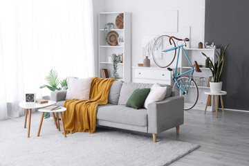 Interior of light living room with comfortable sofa, coffee table and bicycle