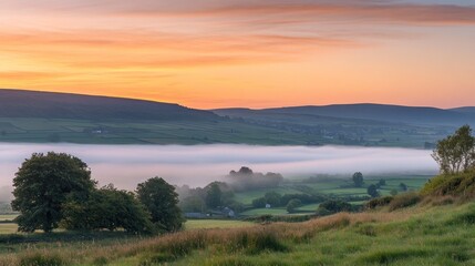 A serene landscape at dawn with mist covering fields and rolling hills.