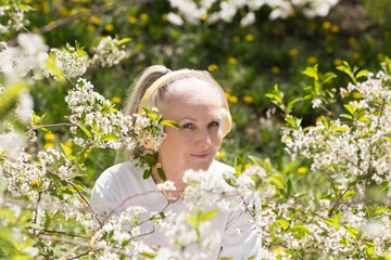  lifestyle portrait smiling senior woman  with gray hair in headphones relaxes in a flowering...