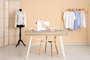 Tailor's workplace with sewing machine, different supplies and mannequin in atelier