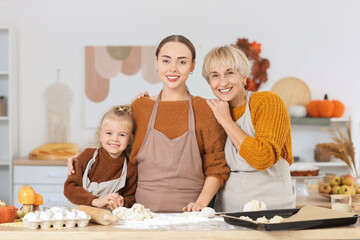 Young woman with her little daughter and mother hugging while baking in kitchen