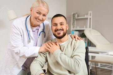 Obraz premium Female doctor hugging young man in wheelchair at hospital