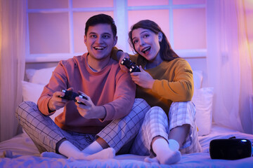 Young couple playing video game in bedroom at night