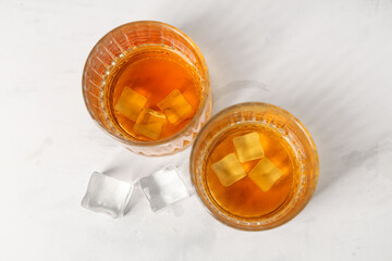 Glasses of rum with ice cubes on white background