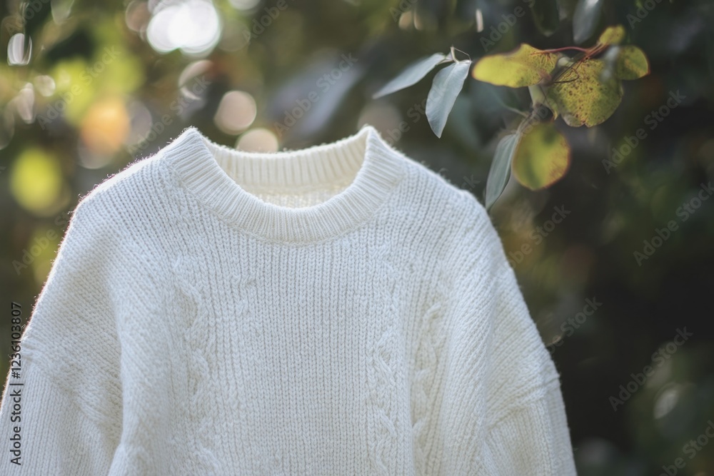 Poster a white sweater hangs from a tree branch in nature