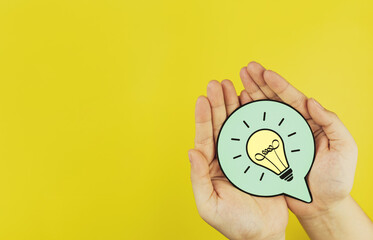 Paper light bulb in hand on yellow background with copy space. Concepts of creativity, innovation,...