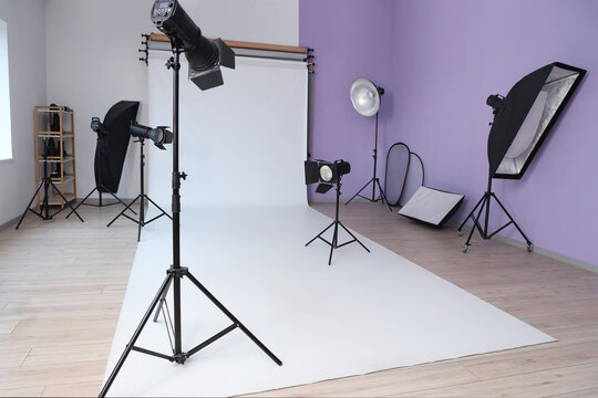 Interior of photo studio with professional lighting equipment and white backdrop
