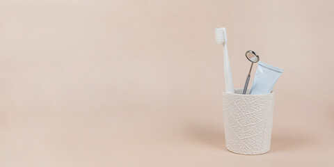 Oral hygiene banner. Toothbrush, dental mirror and toothpaste in the container on a light background. The concept of a healthy lifestyle, self-care, dentistry and dental clinic, oral health. 