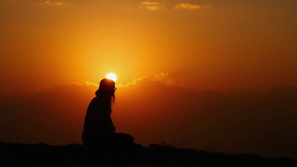 Silhouette of a Woman Standing Against a Vibrant Sunset – Peaceful and Dreamy Scene
