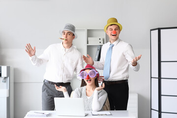 Young colleagues with funny disguise in office. April Fools' Day celebration
