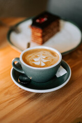 Warm latte art next to a dessert at a cozy cafe in the afternoon