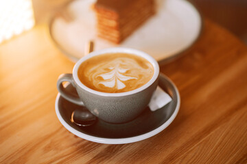Delicious cup of coffee with intricate latte art placed on a wooden table in a cozy cafe setting