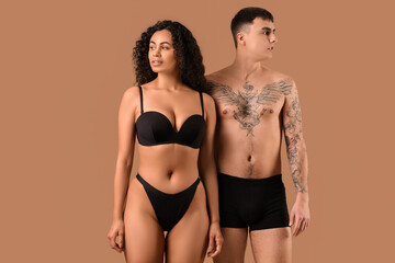 Young couple in stylish underwear on beige background