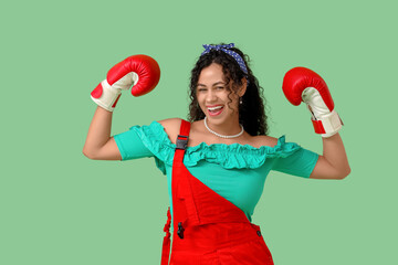 Young African-American pin-up woman with boxing gloves on green background. Women's History Month