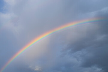 Dark clouds and rainbow in sunset sky. Amazing sky landscape. The sky gives happiness, calmness and peace