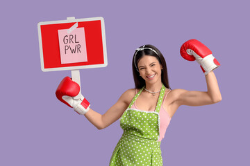 Young pin-up woman in apron with boxing gloves and GRL PWR sign on lilac background. Women's...