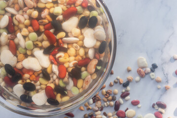 Mixed legumes: peas, lentils, beans, haricot, buckwheat, chickpea soaking with water in a glass bowl.
