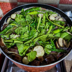 Pork Sinigang topped with chopped water spinach and eggplant.
