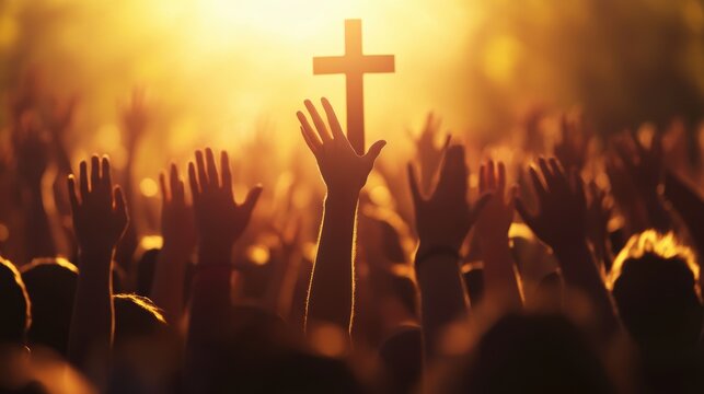 Crowd of worshippers raising hands in gratitude during a religious service, with a silhouette of a cross illuminated by sunlight, symbolizing faith and community.