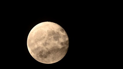 Full moon rises through drifting dark clouds in cinematic time lapse