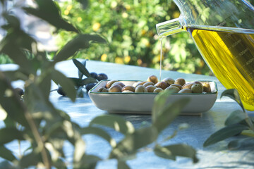 Woman is pouring olive oil on a bowl of fresh olive