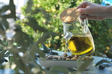 Woman is pouring olive oil on a bowl of fresh olive