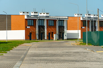 Naklejka premium The exterior of a modern townhouse. The concept of building multi-family residential townhouses. For sale or rent a cozy small house with a beautiful green lawn.