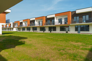 The exterior of a modern townhouse. The concept of building multi-family residential townhouses. For sale or rent a cozy small house with a beautiful green lawn.