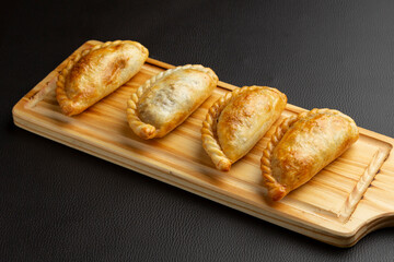 Savory argentinian empanadas resting on rustic wooden surface
