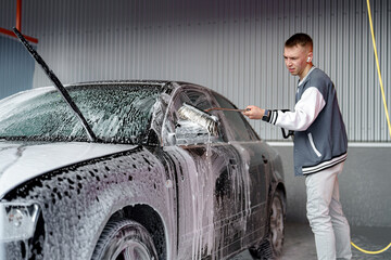 The driver washes the car with a brush and shampoo at the car wash.