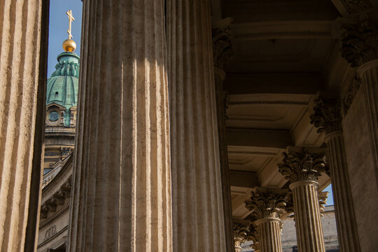 Architecture Kazan Cathedral St. Petersburg. Sunlight highlights intricate details of Grand Architectural Columns foreground, leading eye to historic dome topped with cross and golden orb background