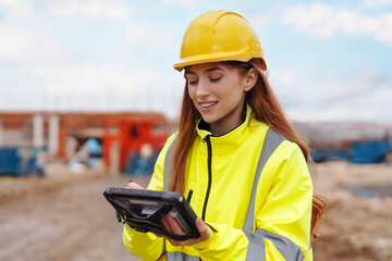 Portrait of a young female site manager  utilizes tablet technology at a worksite 