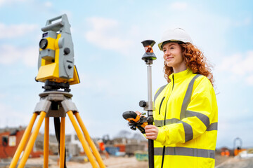 Woman Surveying engineer conducts land measurement with total station equipment at a construction site during a bright day