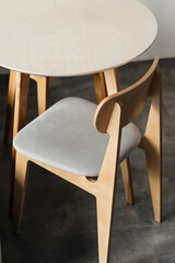 Light plywood chair and table on a gray background of the kitchen interior in the apartment.