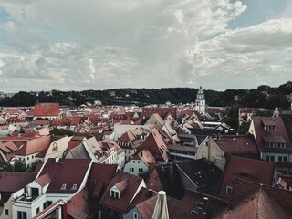 A panoramic view of a historic European town with a sea of red-tiled rooftops and prominent church...