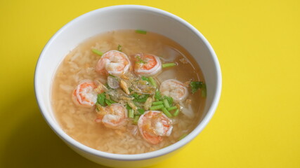 rice soup with shrimp in white bowl on yellow background
