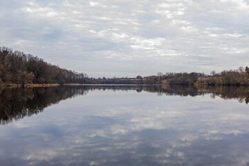 River in the forest. Reflection of trees in the water. Lake in the forest in winter
