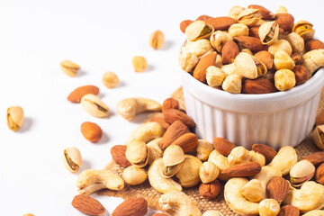 Large assortment of nuts in different bowls on stone table.