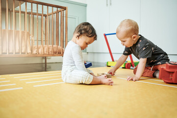 Fototapeta premium Babies playing, home and kid toys for mobility development and learning together in a bedroom. Nursery, toy brick and cute children curious about building blocks and activity in a house on the floor