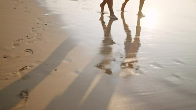 Man, woman feet walk barefoot in sea surf water edge. Reflection of couple with coconut cocktails on wet beach sand. Shadow of people legs going on ocean coastline waves on vacation.
