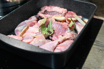 Roasted Rabbit Pieces with Vegetables in a Black Roasting Pan