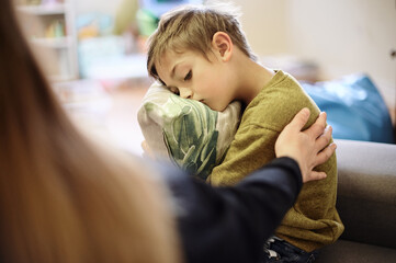 Anxiety, bullying and hand of mother with boy hugging pillow for comfort, compassion and empathy at...