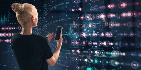 Woman holding smartphone while interacting with digital holographic interface in dark futuristic space.