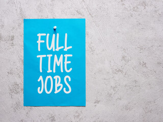 Full time jobs announcement on a blue sheet of paper pinned to a white concrete wall.