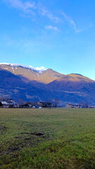 Naklejka premium Beautiful mountains against a blue sky. Houses at the foot of the mountains. Vertical image of majestic mountains.