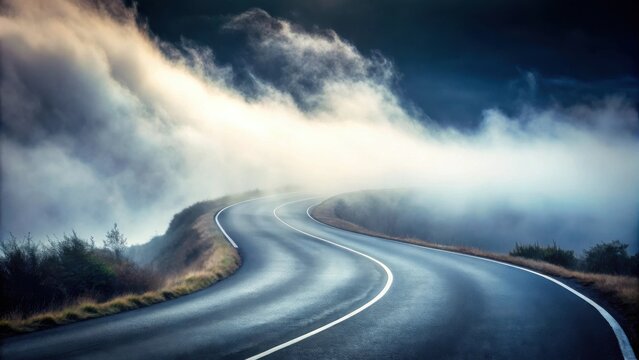 A winding asphalt road disappears into a thick fog, surrounded by rolling hills and a dramatic sky.