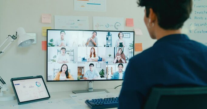 Young freelance Asia male use laptop talk to colleague plan in video call meeting on desk in living room at home office. Work from house, financial plan, remotely digital nomad job and Gen Z talent.