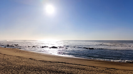 Sandy ocean shore. The sun is shining brightly in the blue sky.