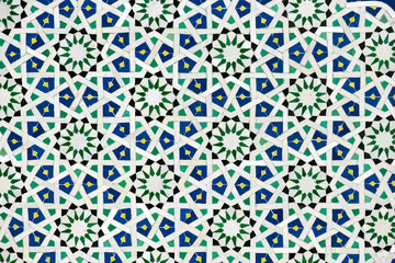 A detailed Islamic geometric mosaic featuring vibrant colors and symmetrical patterns. The design showcases traditional arabesque motifs with star shapes and interwoven lines