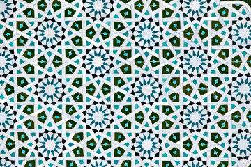 A detailed Islamic geometric mosaic featuring vibrant colors and symmetrical patterns. The design showcases traditional arabesque motifs with star shapes and interwoven lines